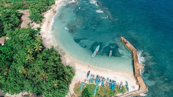 Pantai dengan pasir hitam dan air laut biru di Maluku